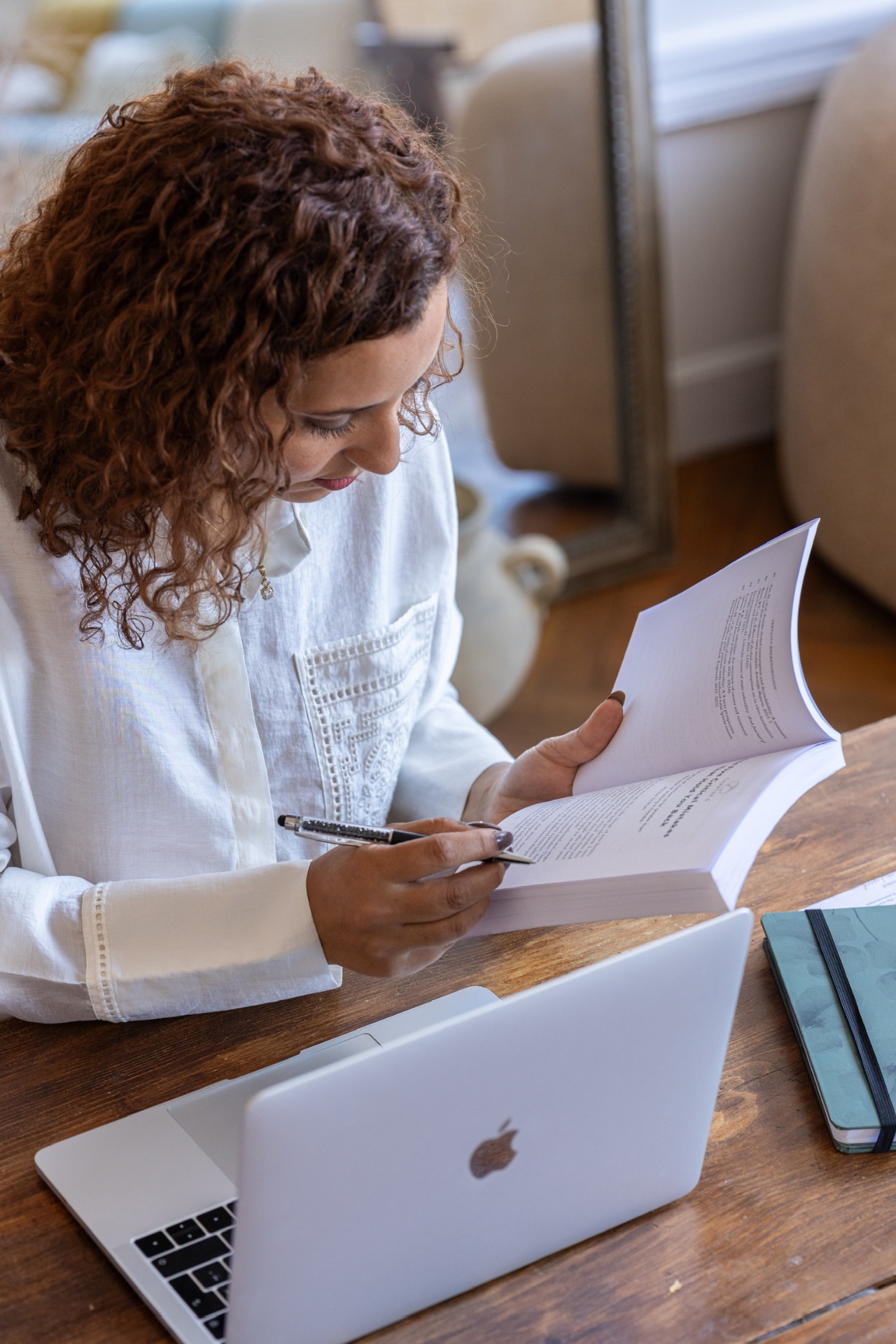 La fondatrice de Fertilience penchée sur son bureau, annotant un livre à côté de son MacBook